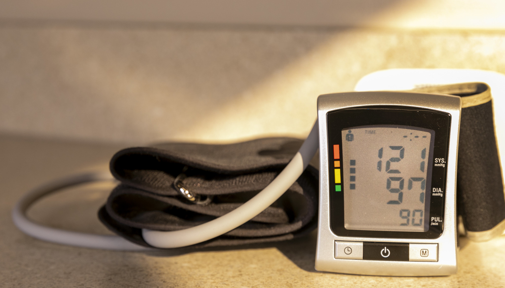 A blood pressure monitor with the arm cuff in the center and the monitor itself on the right.